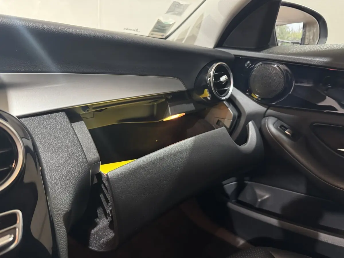 Intérieur noir du Mercedes Classe C Break 2019, vue côté passager avec boîte à gants ouverte et éclairage intérieur.