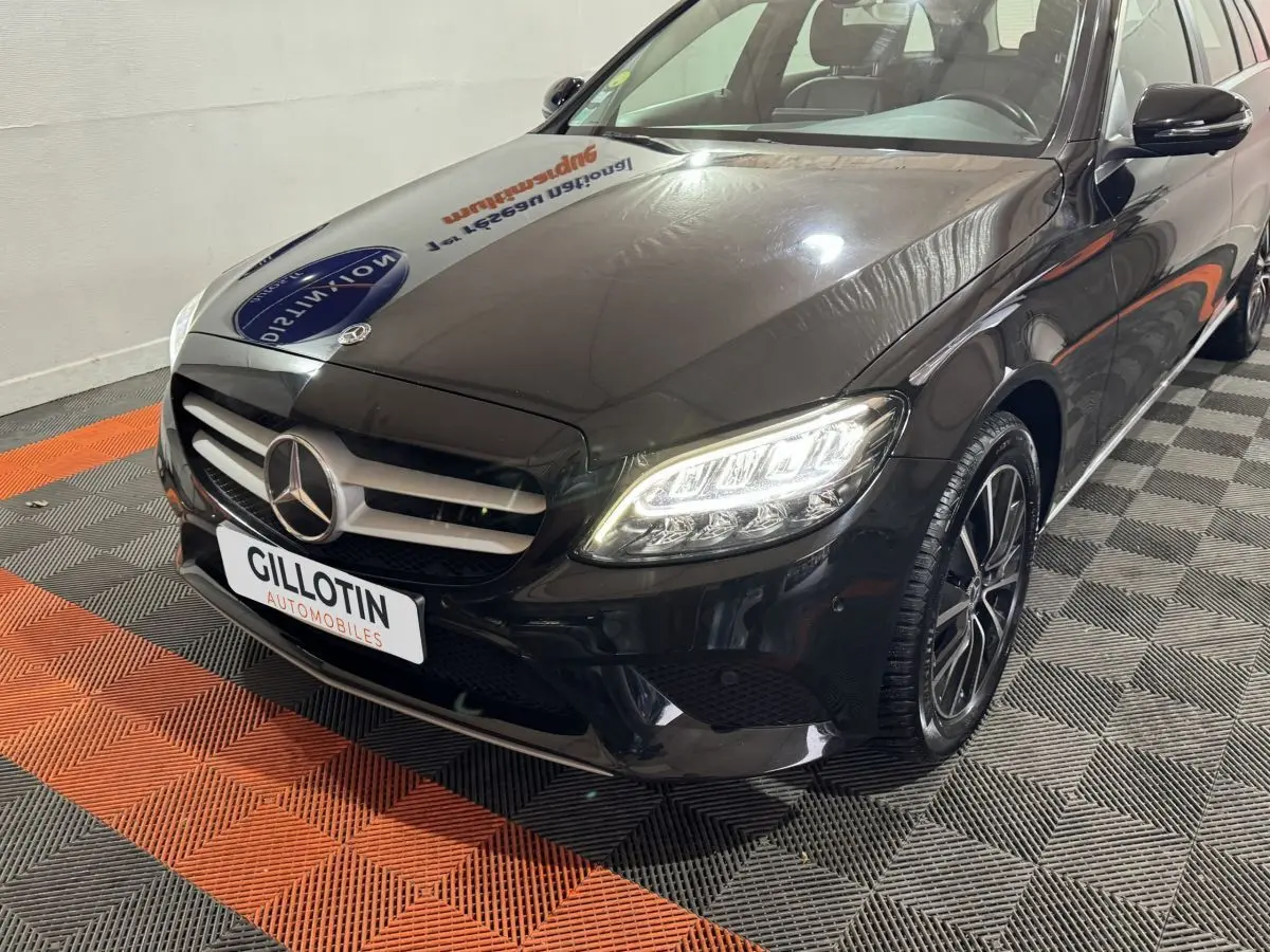 Vue 3/4 avant droite d'une Mercedes Classe C Break C 200 d Business Line noire avec phares LED allumés et jantes alliage.