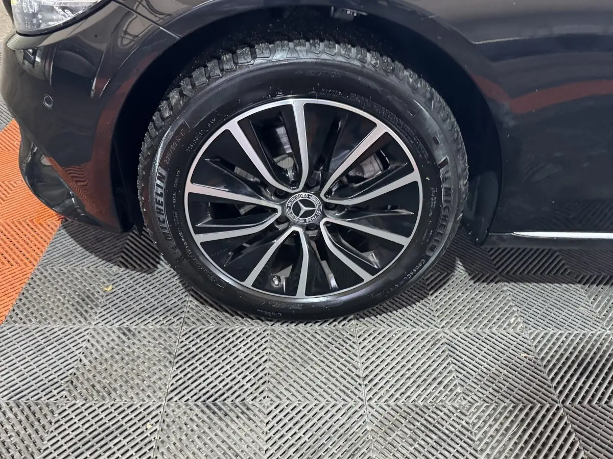 Gros plan sur la roue avant gauche noire d'une Mercedes Classe C Break C 200 d Business Line 2019 avec jante alliage bicolore.