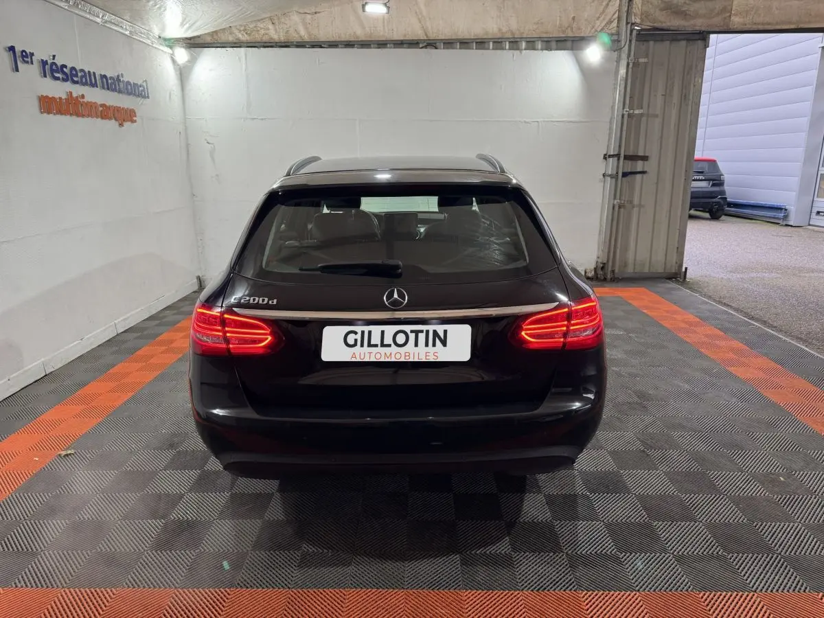 Vue arrière d'un break Mercedes Classe C 200 d noir avec feux arrière allumés dans un garage.