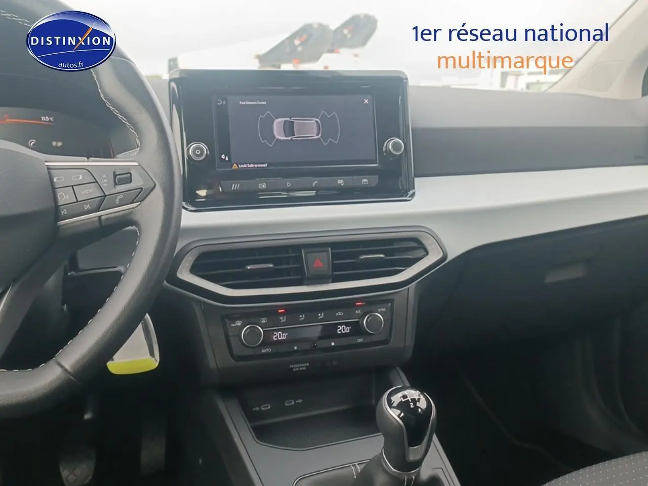 Vue intérieure centrée sur la console centrale et le volant cuir noir de la SEAT Ibiza blanc Nevada 2025 avec boîte manuelle.