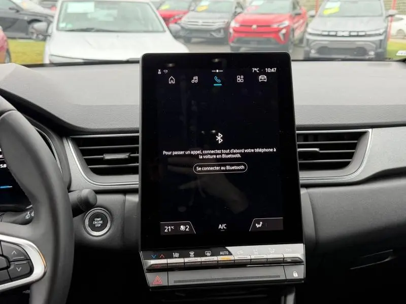 Vue intérieure centrée sur l'écran tactile du tableau de bord du Renault Captur 2025, avec volant partiel visible.
