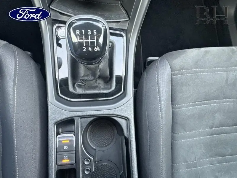 Vue rapprochée de la console centrale d'une Volkswagen Touran 2021 avec levier de vitesse manuel et sièges gris.