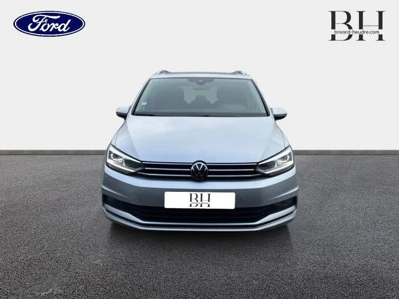 Vue de face d'un Volkswagen Touran 1.5 TSI Carat 7 places en Reflet d'Argent Métallisée avec calandre chromée.