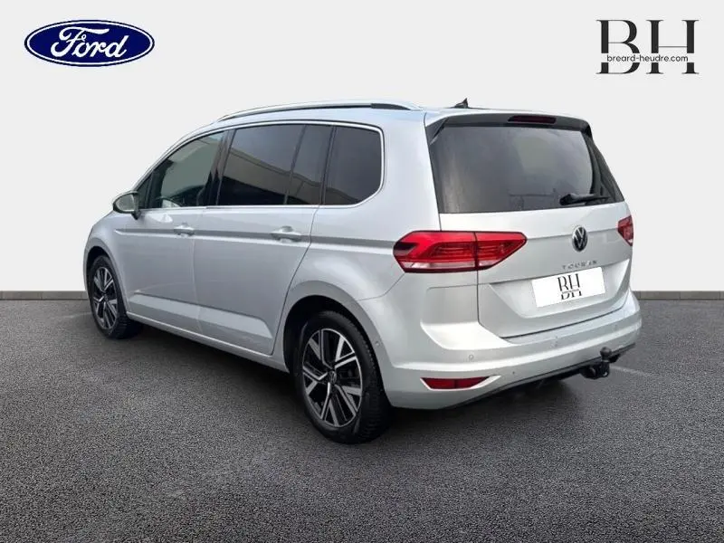 Vue 3/4 arrière droite d’un Volkswagen Touran 2021 Reflet d’Argent Métallisée avec attelage et vitres arrière surteintées.