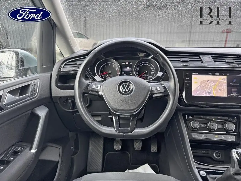 Vue intérieure centrée sur le volant multifonction et tableau de bord du Volkswagen Touran 1.5 TSI en Reflet d'Argent.