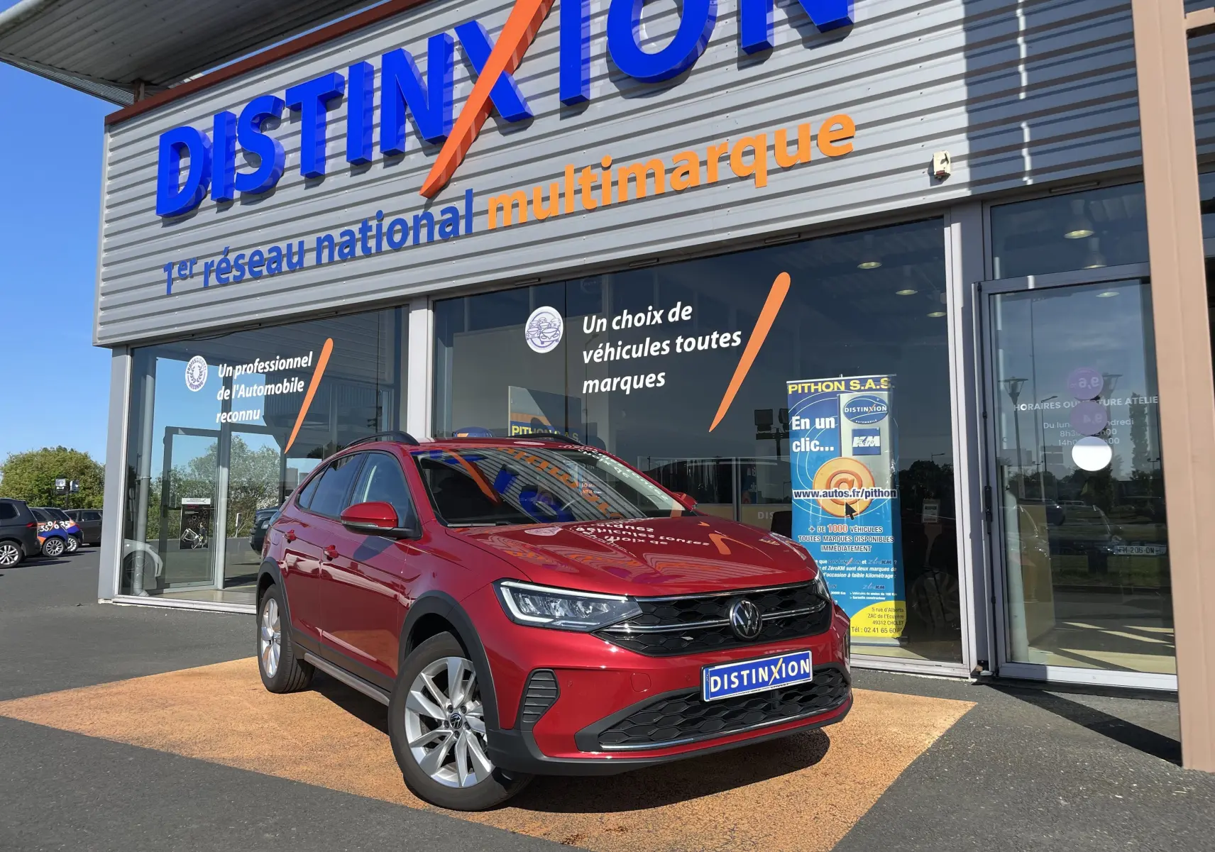 Volkswagen Taigo rouge roi en 3/4 avant droit devant un showroom Distinxion, avec jantes alliage et calandre noire.