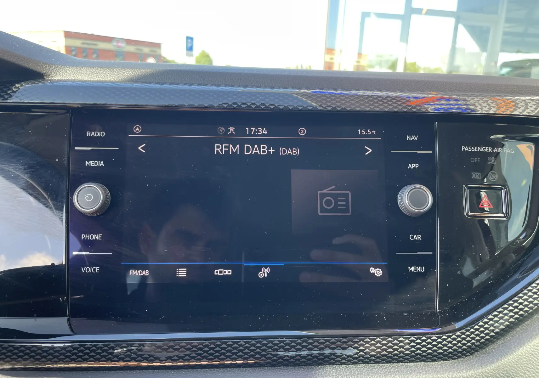 Tableau de bord du Volkswagen Taigo 2024 avec écran tactile central allumé, entouré d’un cadre noir texturé.