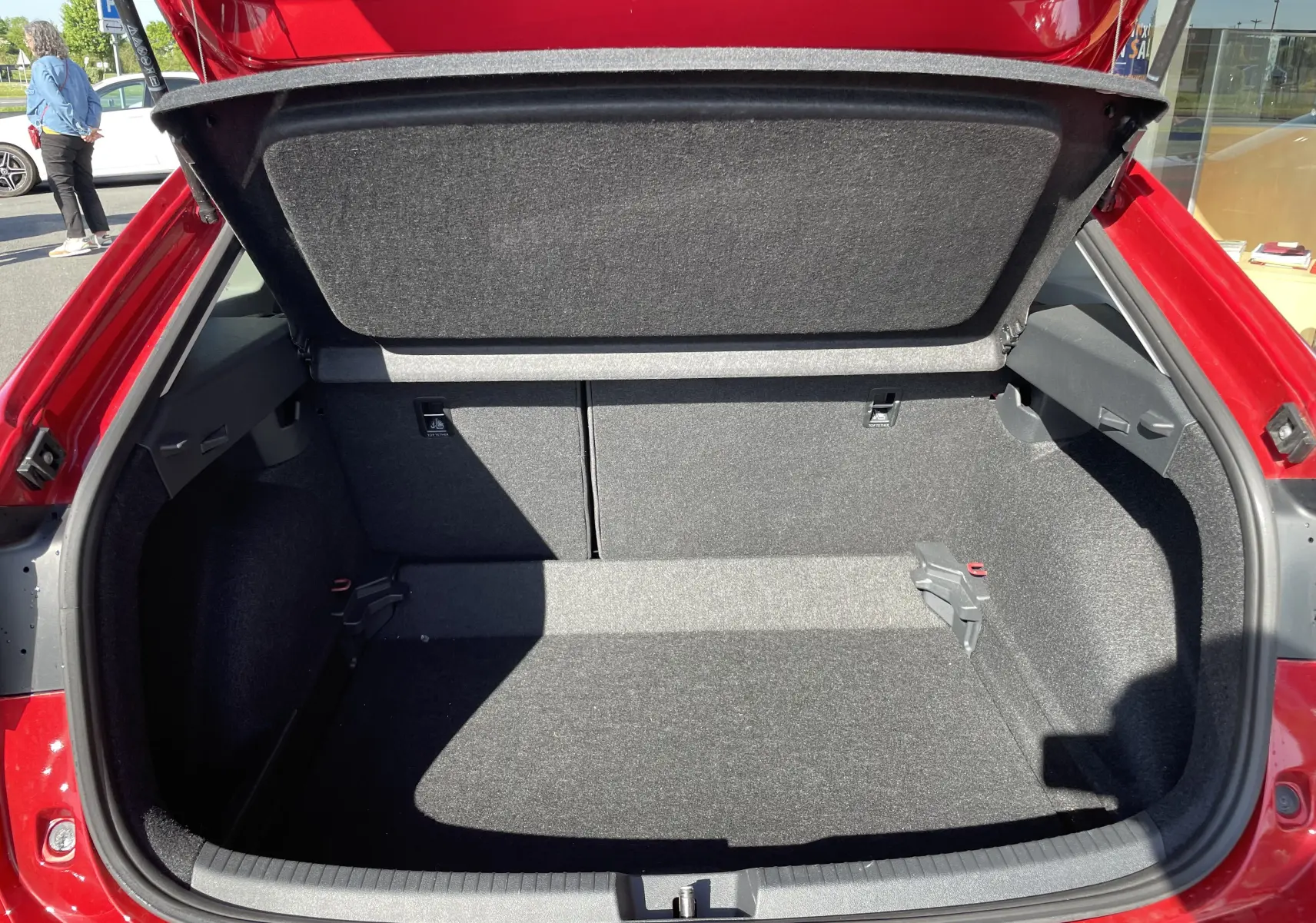 Coffre ouvert vu de l'arrière d'un Volkswagen Taigo rouge Roi 2024, montrant l'espace de chargement vide et doublé de tissu gris.