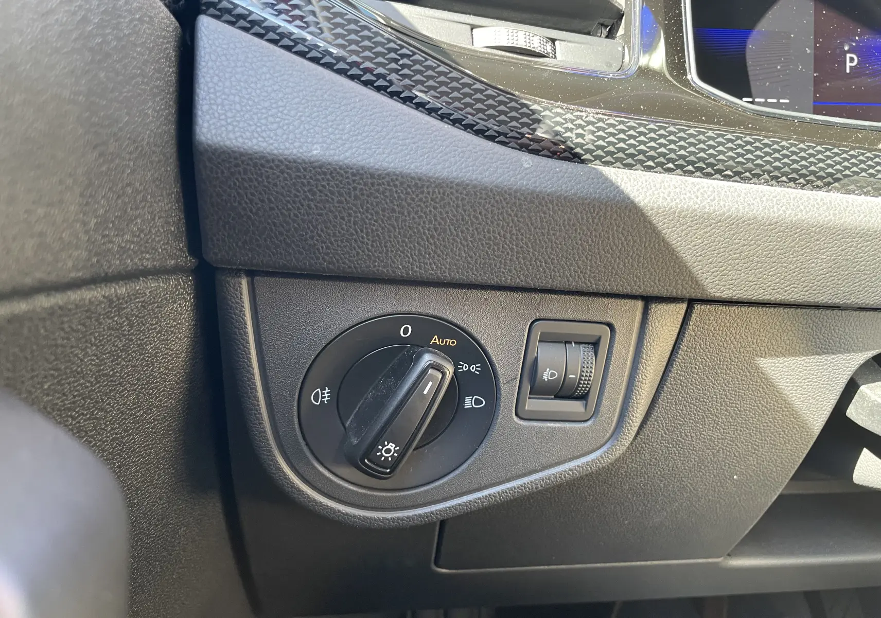 Détail du tableau de bord côté gauche du Volkswagen Taigo 2024 rouge roi, montrant la commande des phares et le réglage d'intensité.