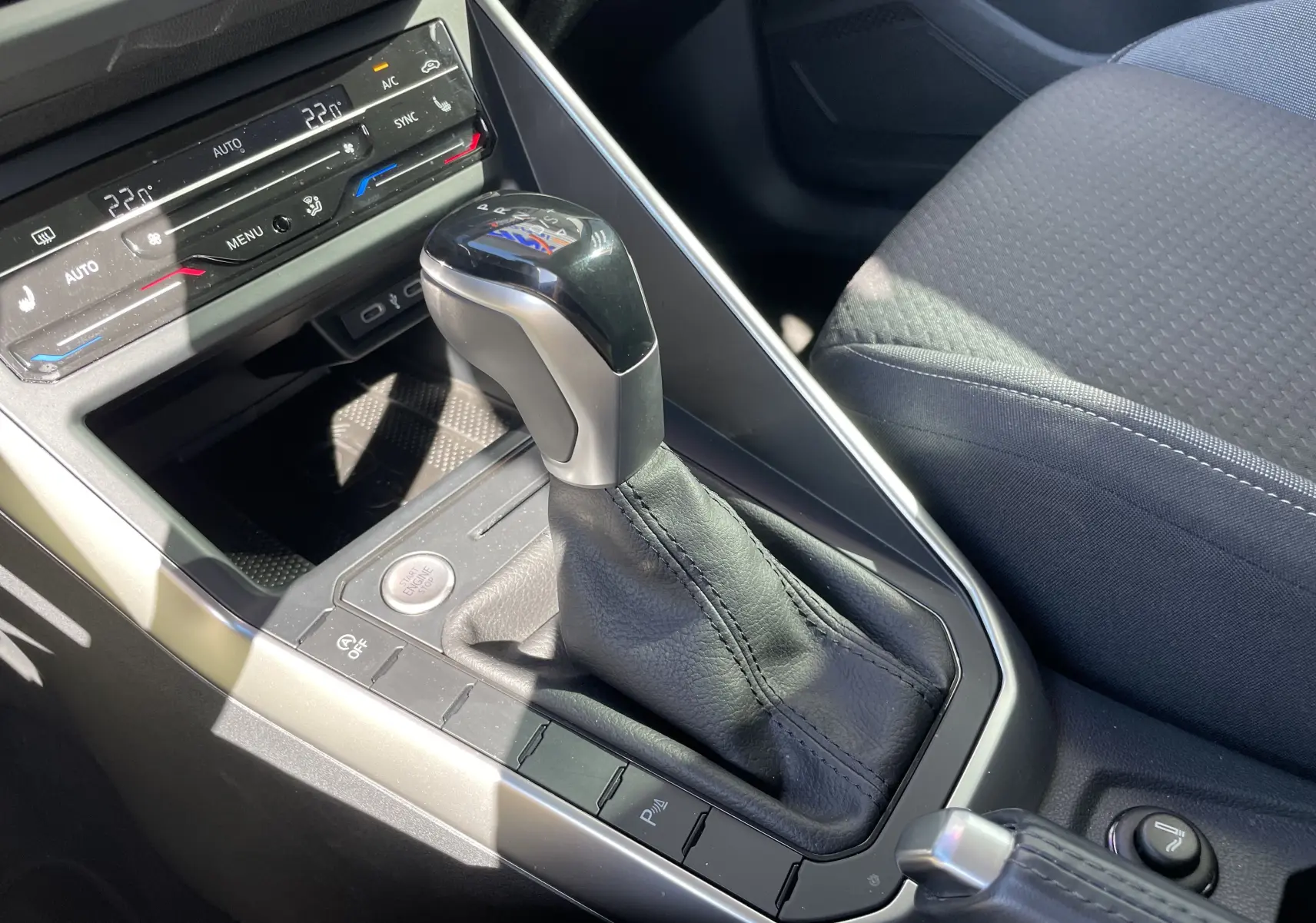 Vue rapprochée de la console centrale du Volkswagen Taigo 2024, avec levier de vitesse automatique et sellerie tissu gris.