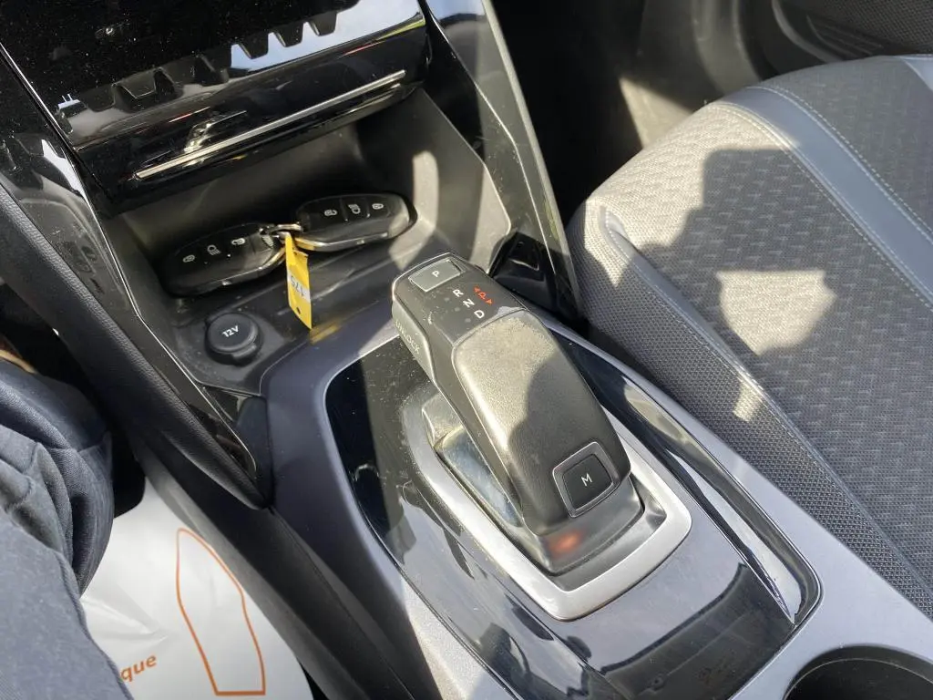 Gros plan sur la console centrale de la Peugeot 2008 2020, montrant le levier de boîte auto et les clés sur fond noir brillant.