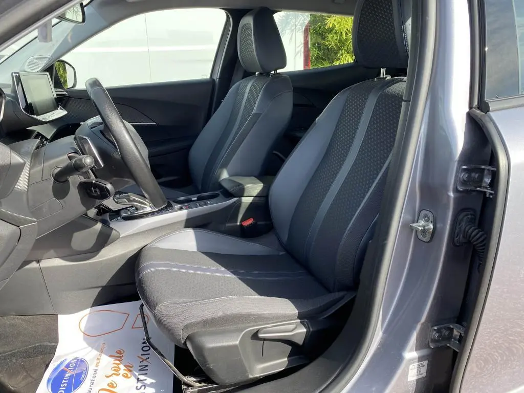 Vue intérieure côté conducteur de la Peugeot 2008 gris clair, montrant les sièges avant et la console centrale avec boîte auto.