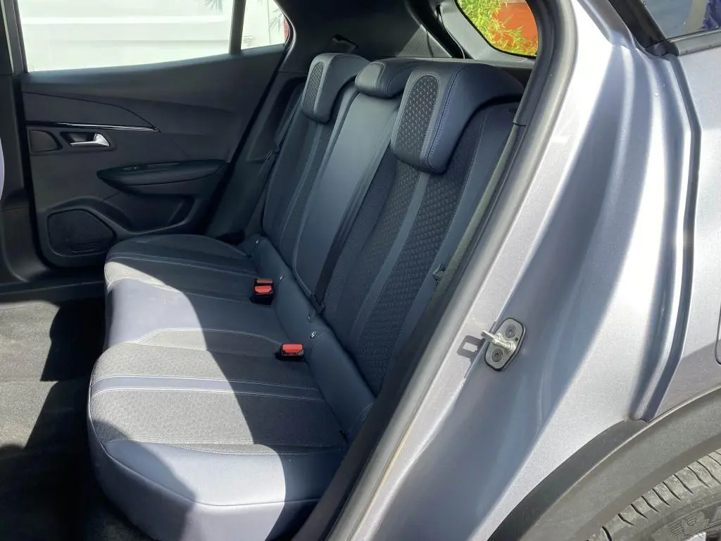 Vue côté droit arrière du Peugeot 2008 gris clair, montrant les sièges arrière en tissu et cuir avec appuie-têtes intégrés.