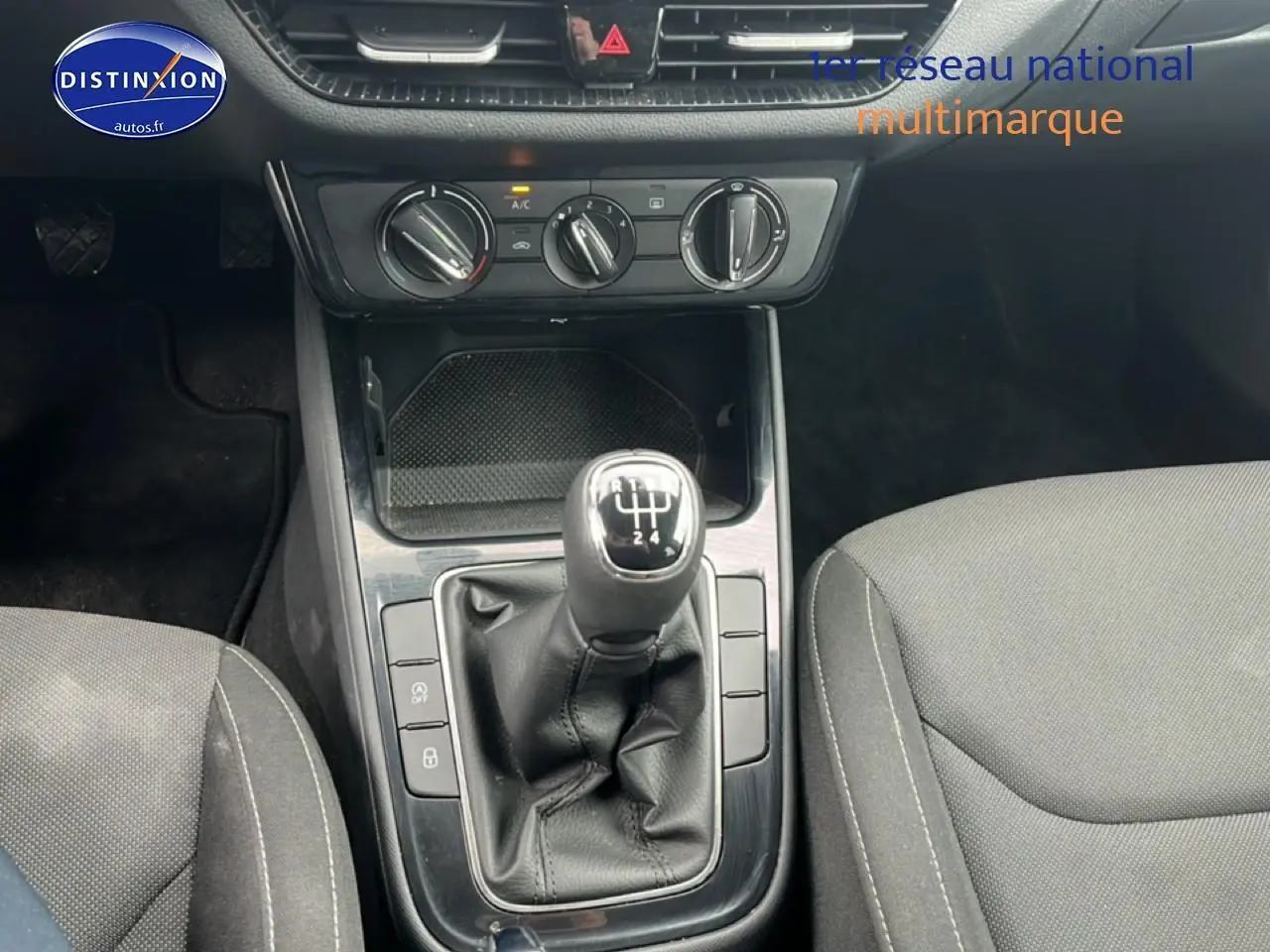 Vue rapprochée de la console centrale noire avec levier de vitesse manuel et sièges tissu gris d’une Skoda Fabia blanche.