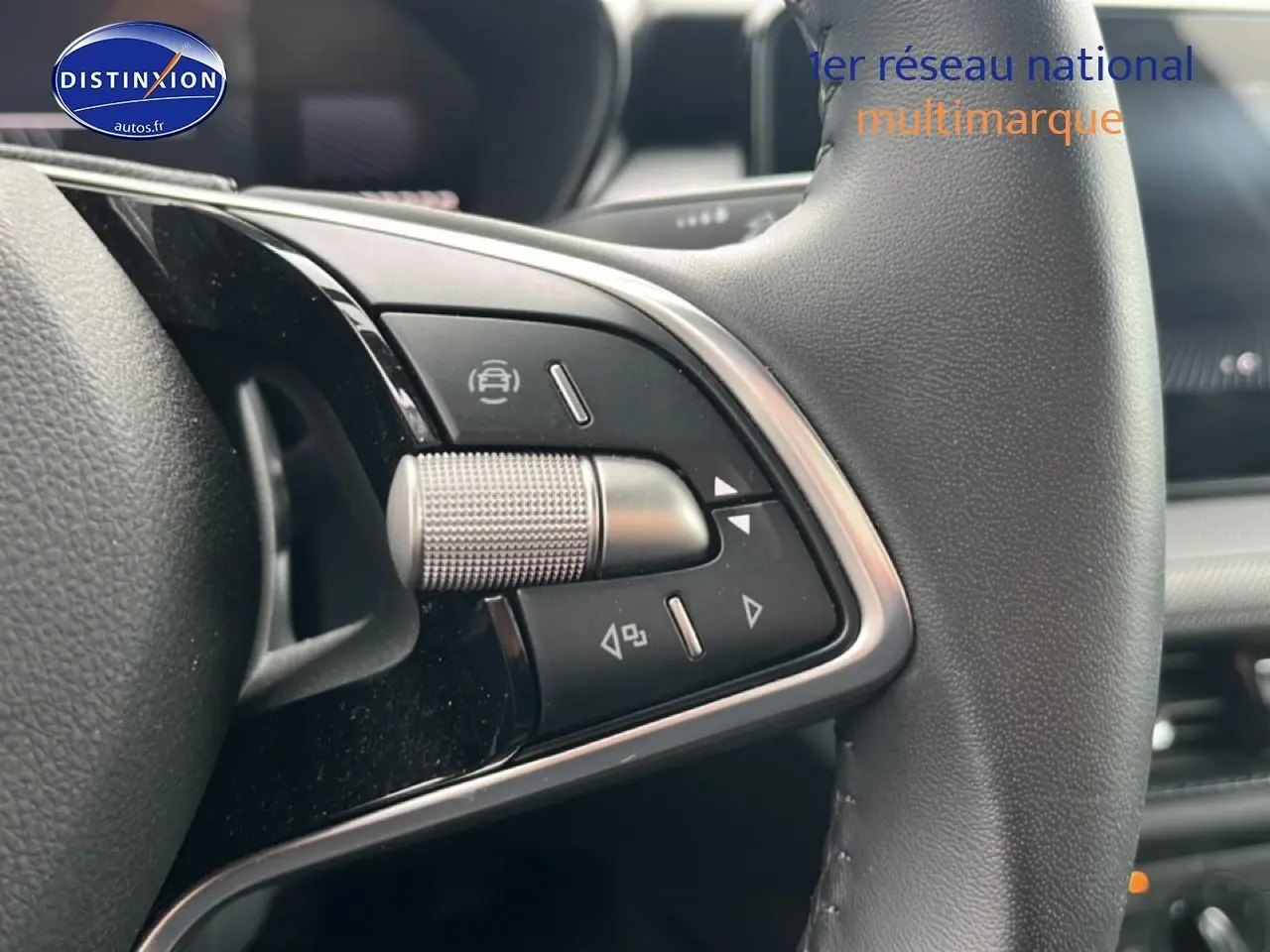 Gros plan sur les commandes multifonctions en métal et plastique noir du volant cuir d'une Skoda Fabia blanche 2025.