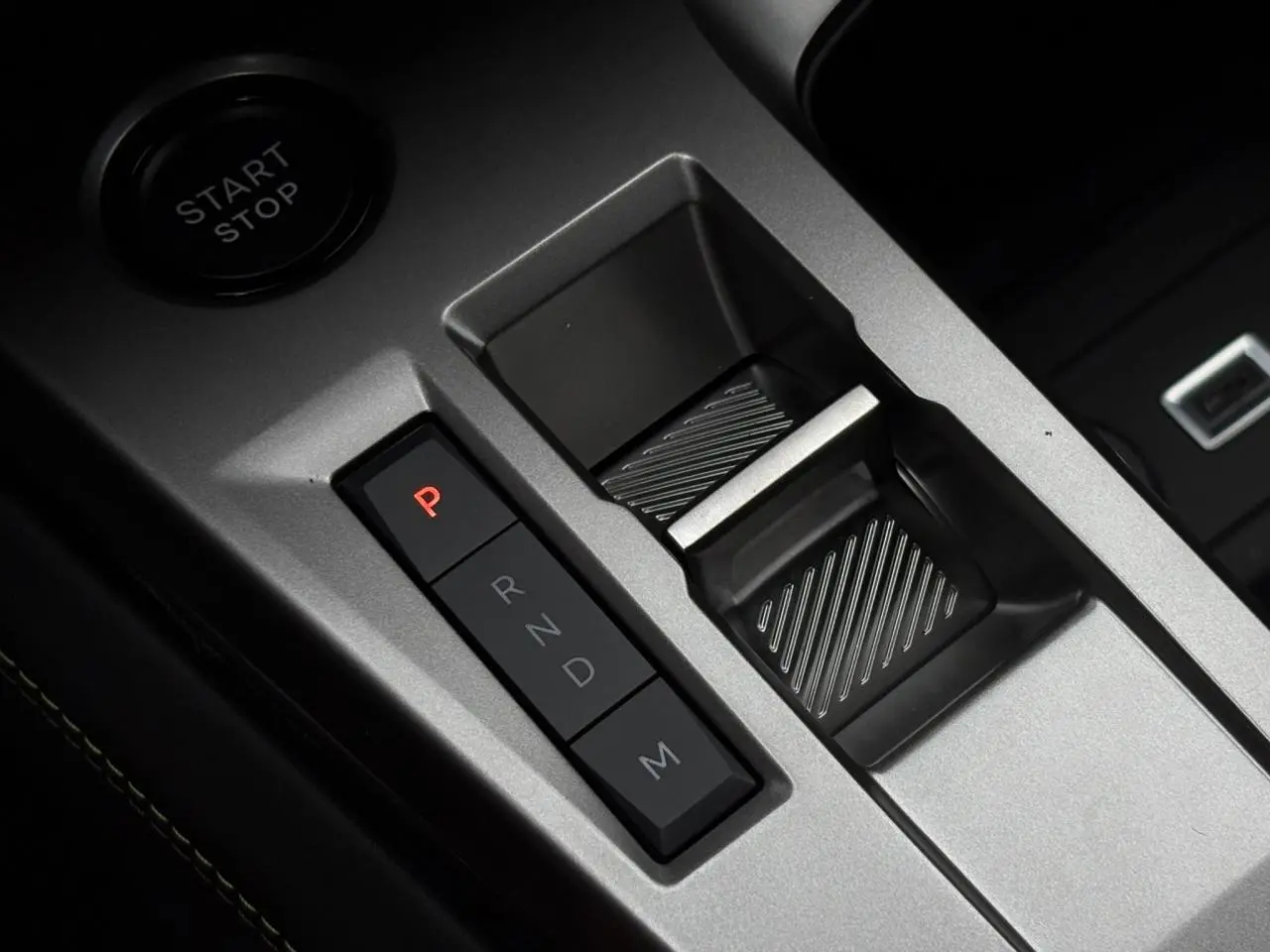 Gros plan sur la commande de boîte automatique et bouton start/stop dans l'intérieur gris aluminium du Peugeot 308 SW Hybrid.