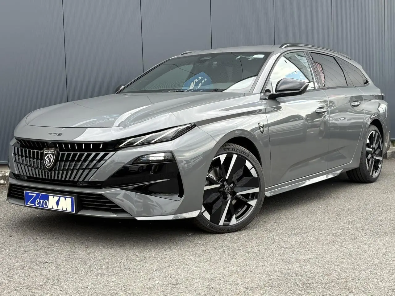 Peugeot 308 SW gris Sélénium vue 3/4 avant avec jantes alliage noires et calandre distinctive moderne.