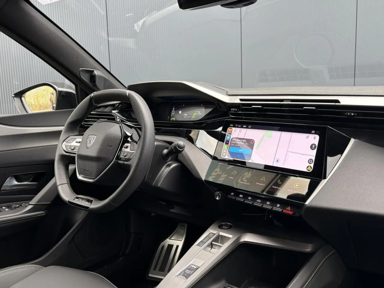 Vue intérieure côté conducteur du Peugeot 308 SW gris, avec volant compact GT et écran tactile central lumineux.