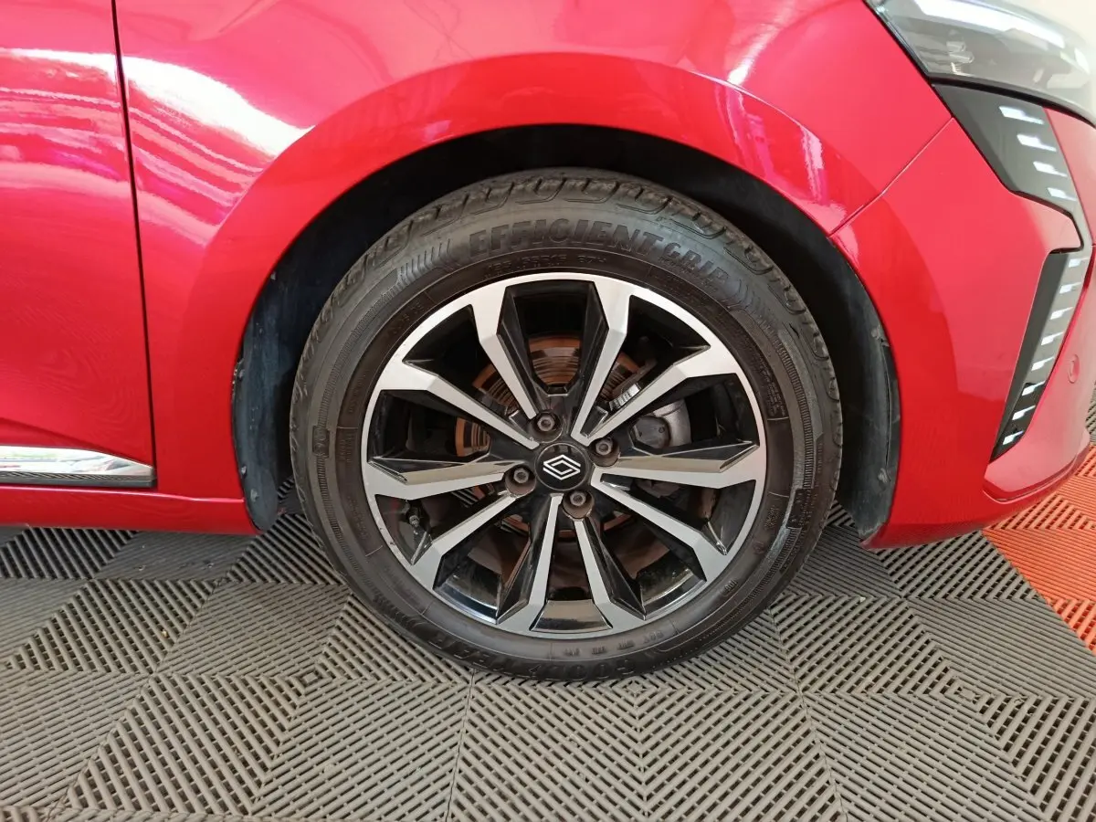 Gros plan sur la roue avant droite d'une Renault Clio Techno TCe 90 rouge 2024 avec jante alliage noire et argent.