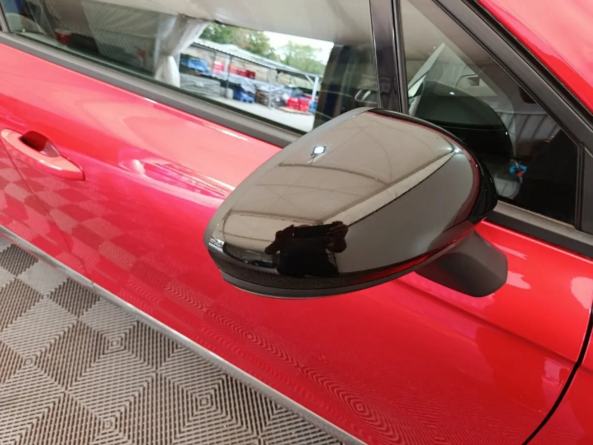 Rétroviseur noir brillant côté gauche sur porte rouge vif d'une Renault Clio Techno TCe 90 -24 vue de profil rapproché.