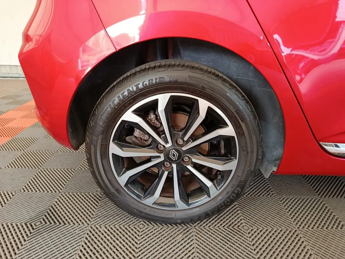Gros plan sur la roue arrière droite d’une Renault Clio rouge 2024 avec jante alliage bicolore et logo Renault central.