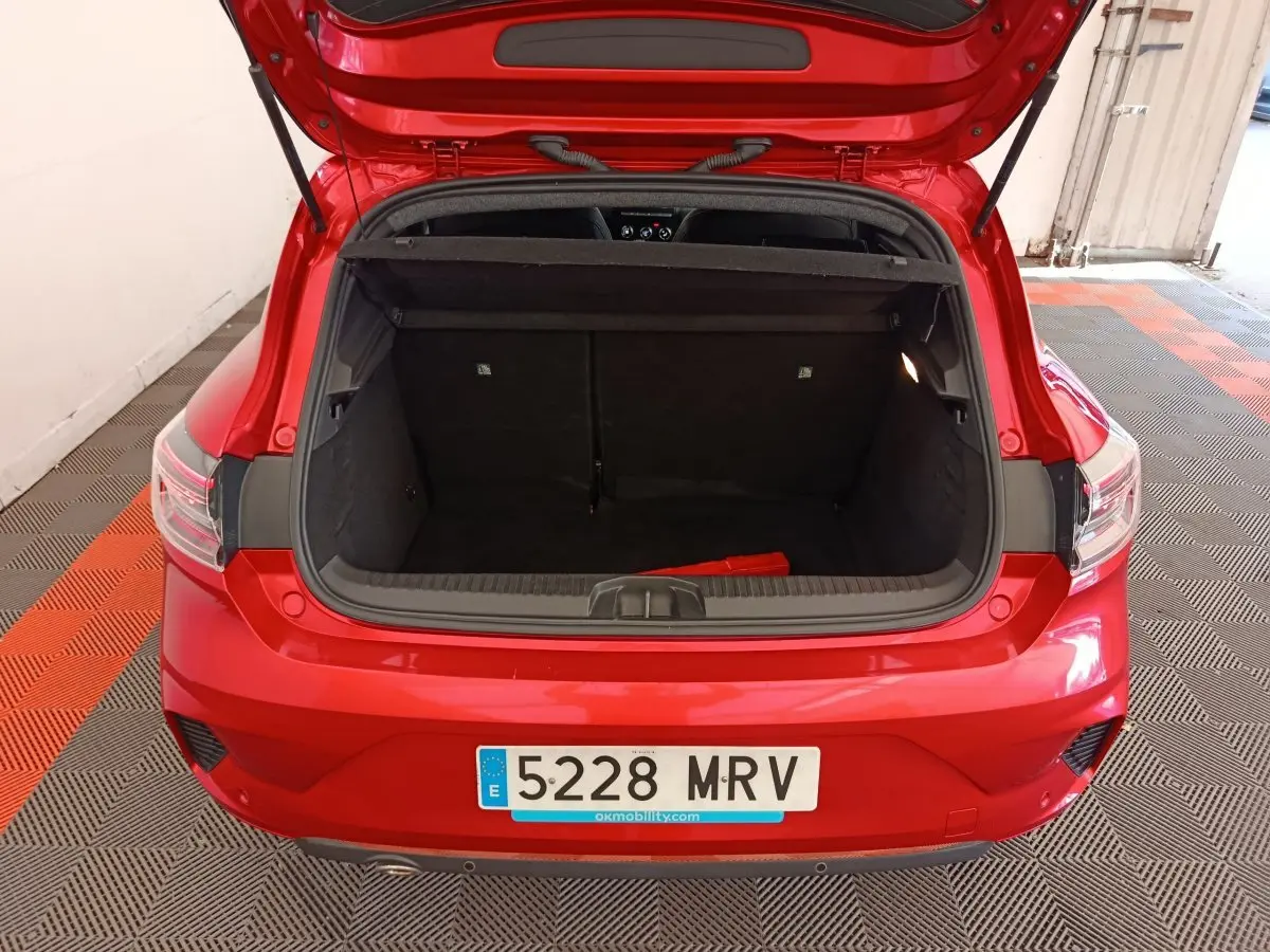 Vue arrière ouverte du coffre d'une Renault Clio Techno TCe 90 rouge 2024, montrant l'espace de chargement vide.