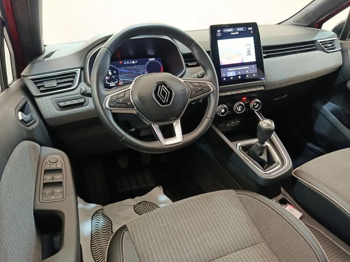 Vue intérieure avant de la Renault Clio Techno TCe 90 2024, volant cuir, écran tactile vertical et boîte manuelle.