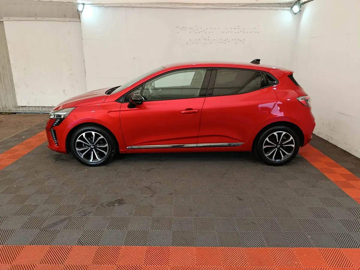 Profil côté gauche de la Renault Clio Techno TCe 90 rouge 2024, avec jantes alliage et vitres teintées.