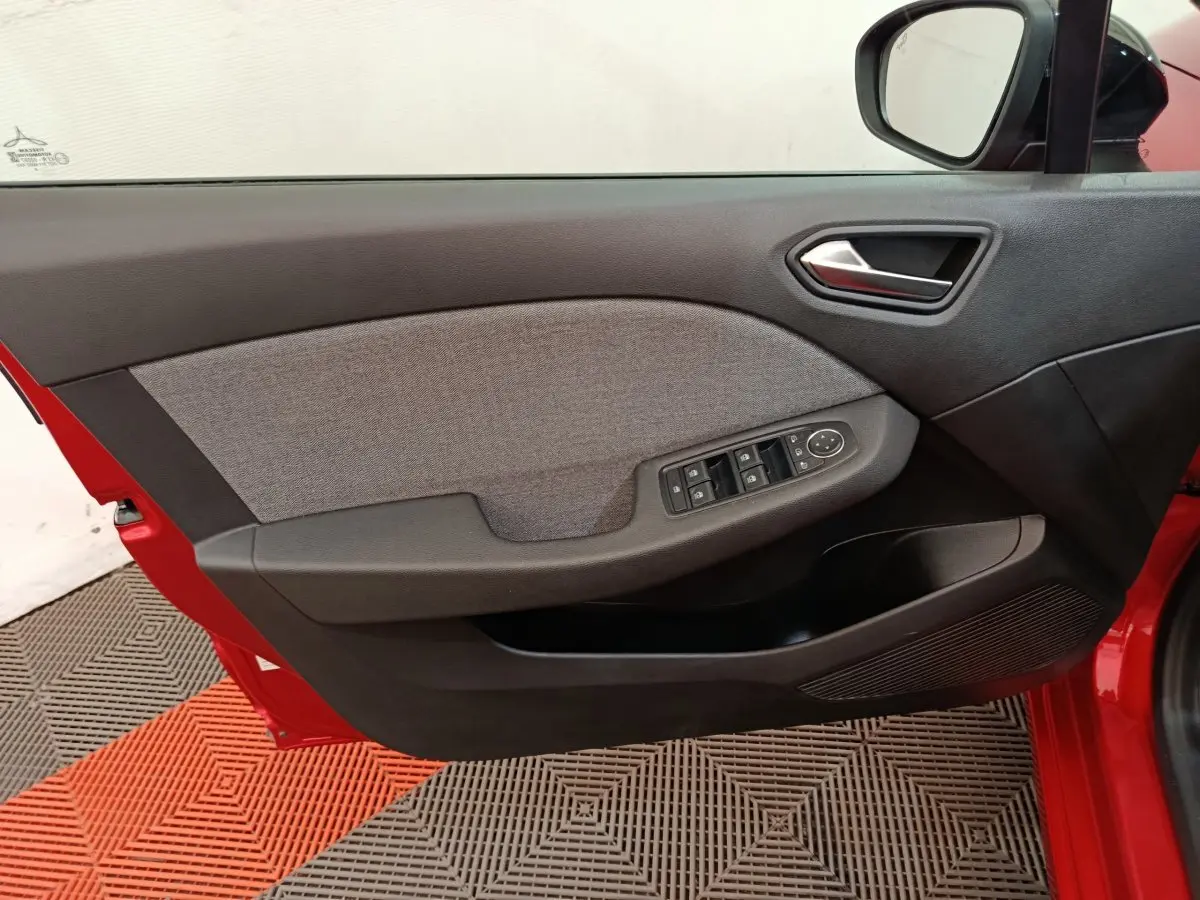 Vue intérieure de la porte avant gauche rouge de la Renault Clio 2024, avec commandes électriques et habillage tissu gris.