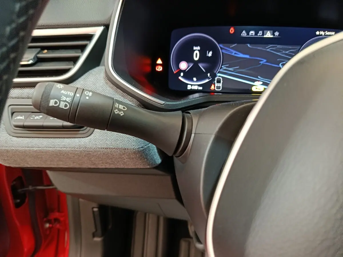 Vue rapprochée du combiné d'instruments numérique et du commodo gauche dans l'habitacle rouge de la Renault Clio Techno TCe 90 2024.