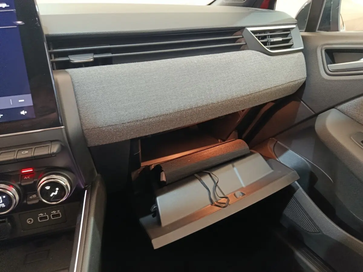 Intérieur de la Renault Clio Techno TCe 90 2024, vue côté passager avec boîte à gants ouverte et tableau de bord gris.
