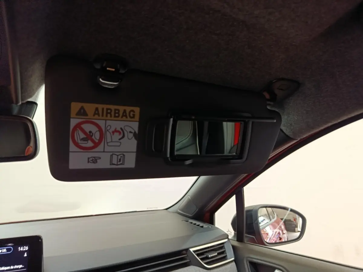 Intérieur de la Renault Clio Techno TCe 90 2024 rouge, vue côté passager avec pare-soleil et miroir ouvert.