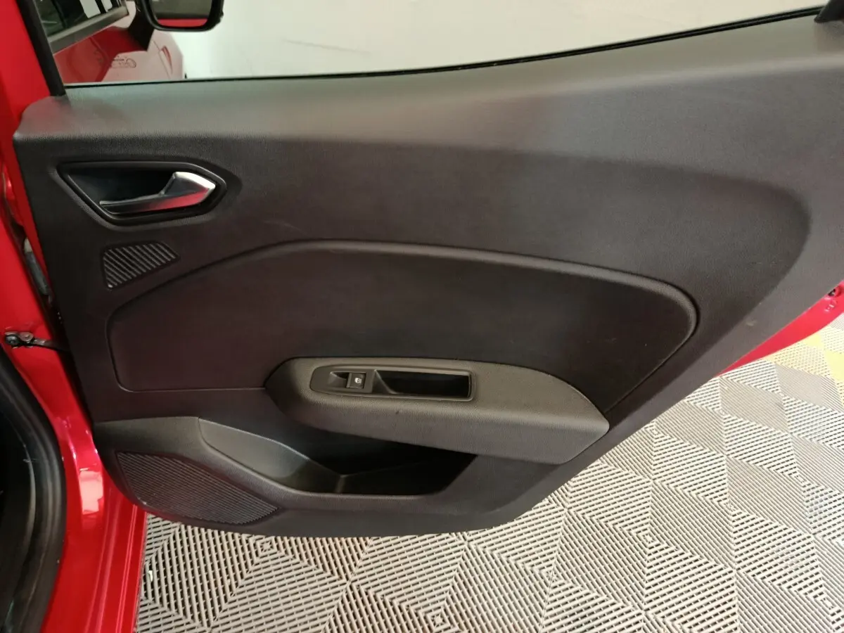 Vue intérieure de la porte avant gauche rouge de la Renault Clio 2024 avec poignée et commande de vitre.