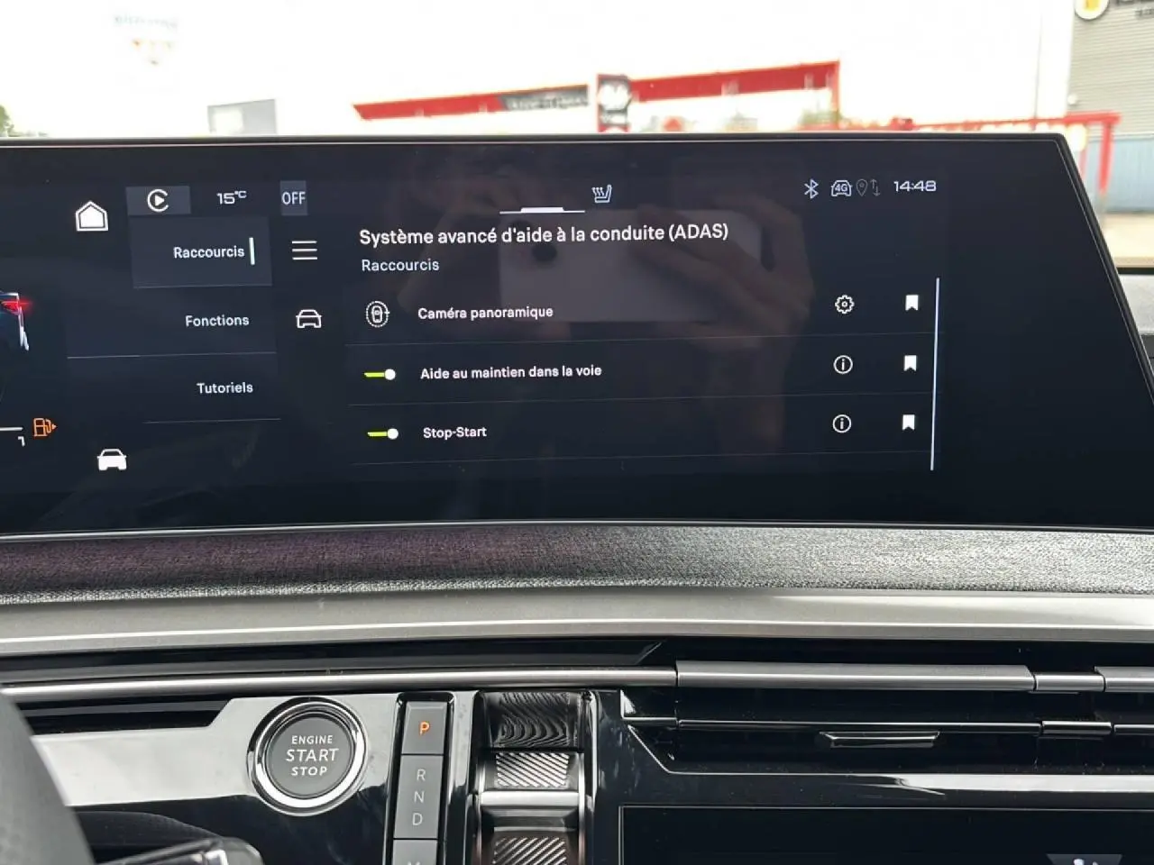 Vue intérieure du tableau de bord du Peugeot 3008 Hybrid 2026, écran tactile affichant l'aide à la conduite, bouton démarrage visible.