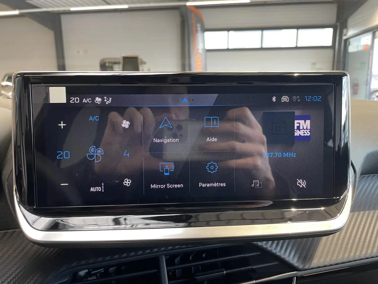 Écran tactile central du Peugeot 208 2025 affichant la climatisation et les options multimédia, avec cadre noir brillant.