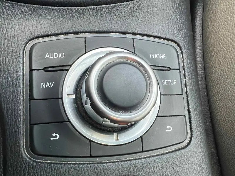 Gros plan sur le bouton de commande centrale multimédia noir du Mazda CX-5 2013, entouré de touches audio, nav, phone et setup.