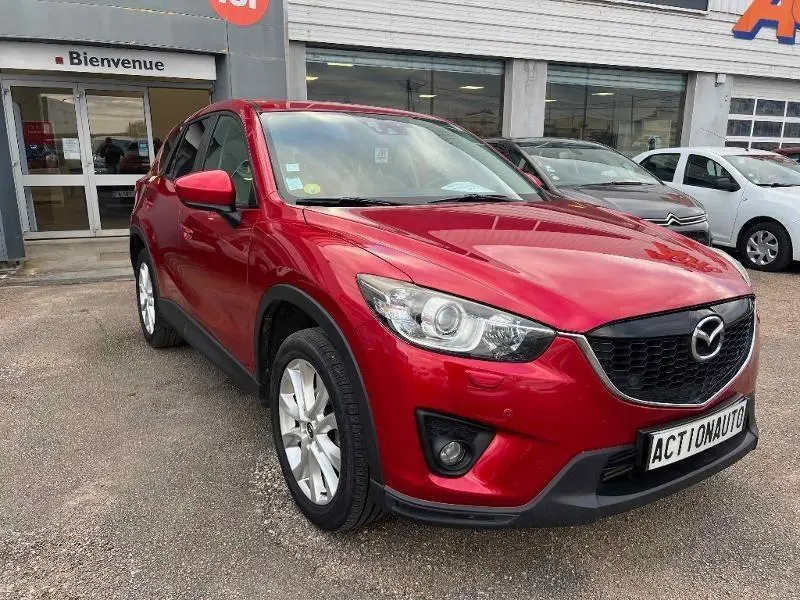 Vue 3/4 avant d'un Mazda CX-5 rouge Soul Red Métallisé avec calandre noire et jantes alu 19 pouces.