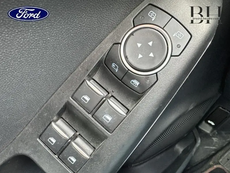 Gros plan sur les commandes de lève-vitres et réglages des rétroviseurs côté conducteur du Ford Puma blanc.