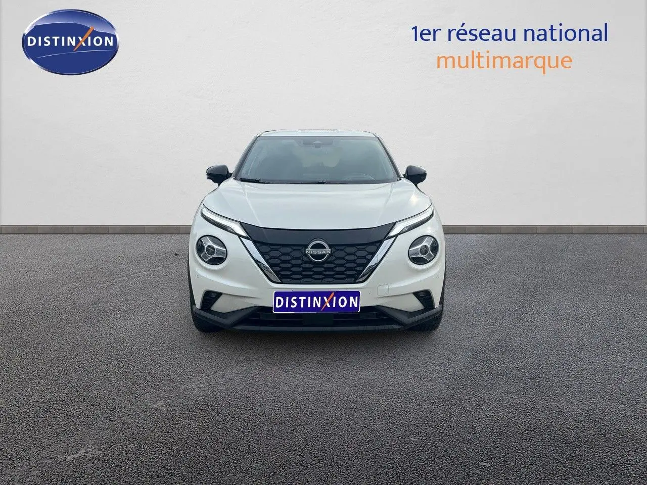 Vue frontale d'un Nissan Juke blanc nacré métal 2024 avec calandre noire et phares ronds LED.