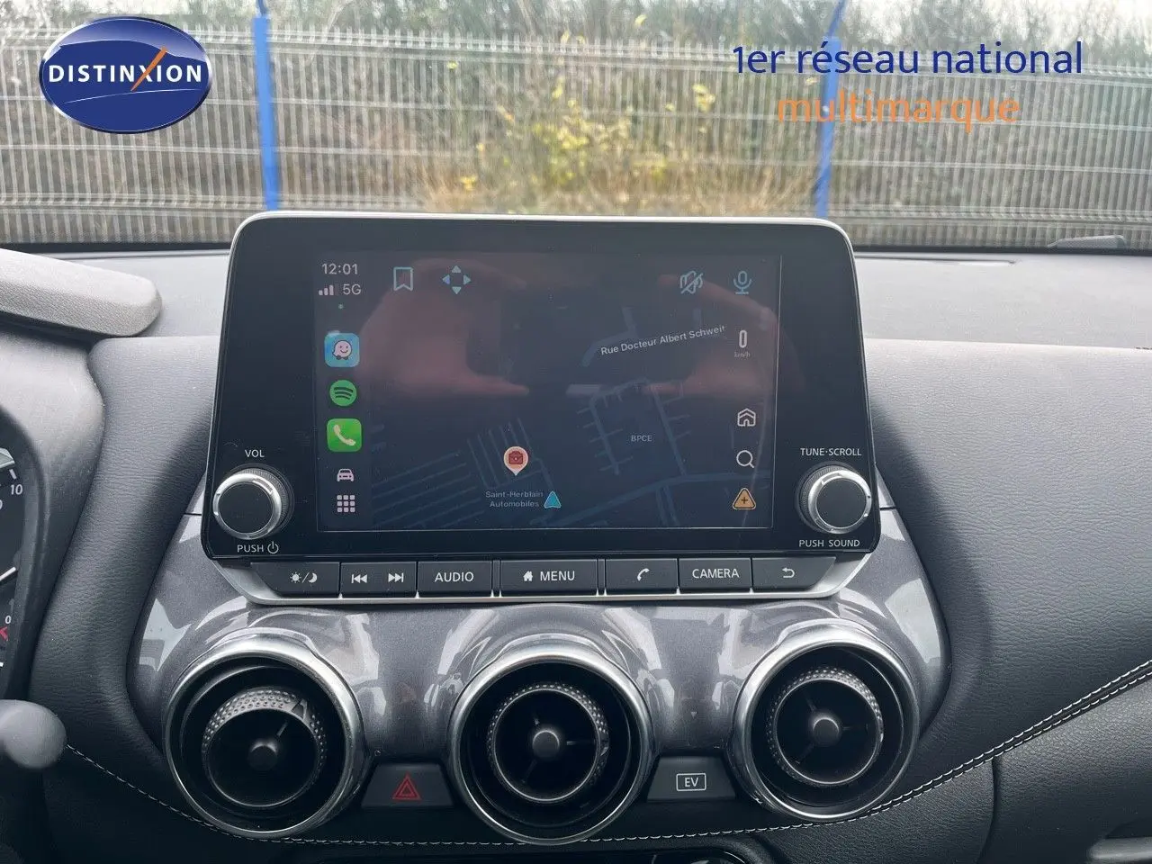 Vue rapprochée de la console centrale du Nissan Juke 2024, écran tactile avec navigation et aérateurs ronds chromés.