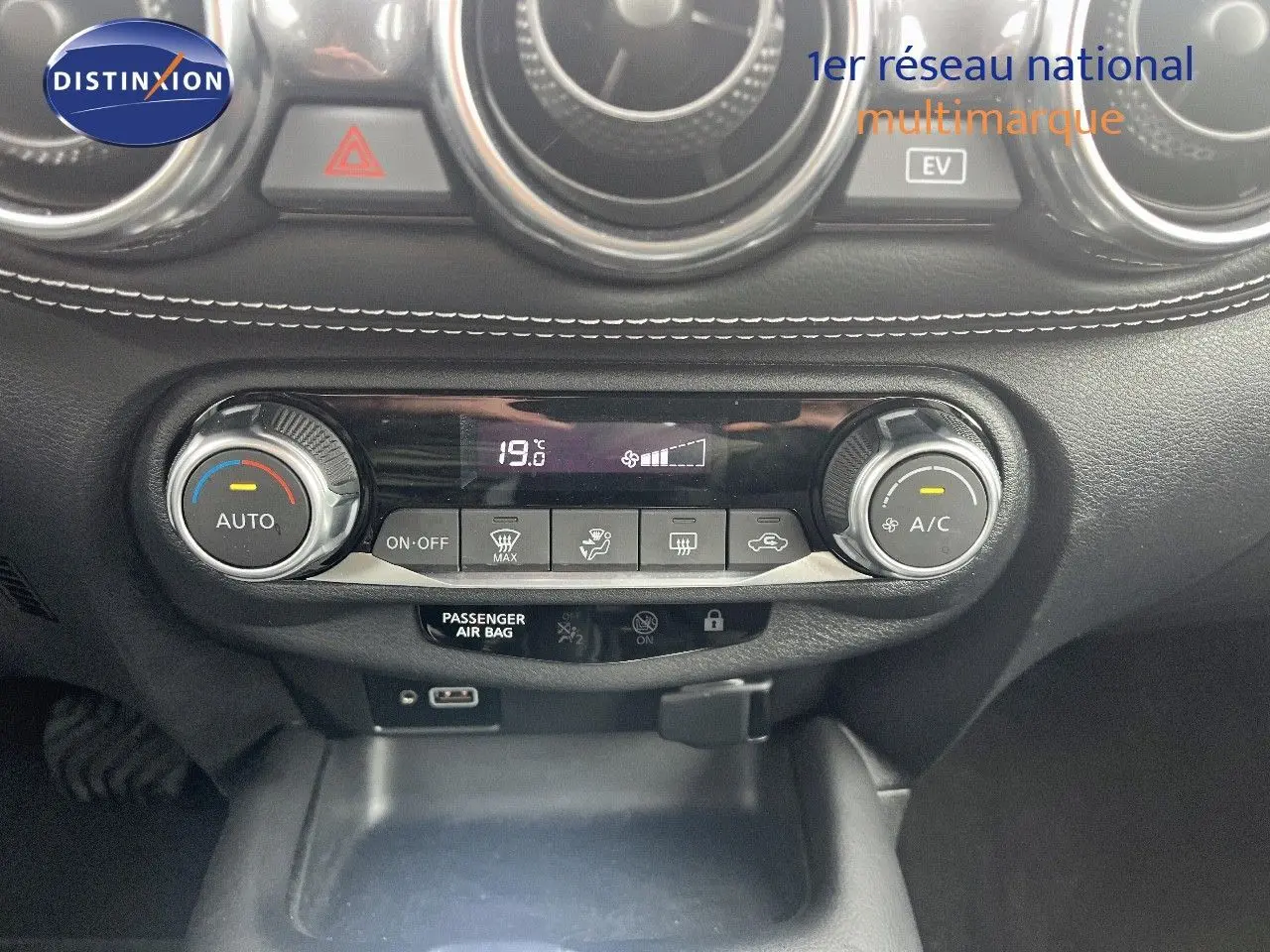 Gros plan sur la console centrale noire avec commandes de climatisation et affichage digital du Nissan Juke blanc nacré 2024.