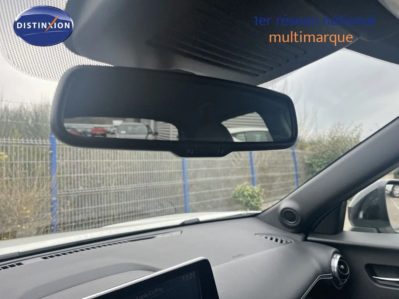 Intérieur du Nissan Juke blanc nacré, vue du tableau de bord côté passager avec rétroviseur et écran tactile allumé.