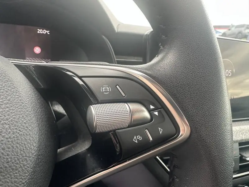 Gros plan sur les commandes multifonctions en aluminium brossé du volant cuir noir du Skoda Scala 2025.
