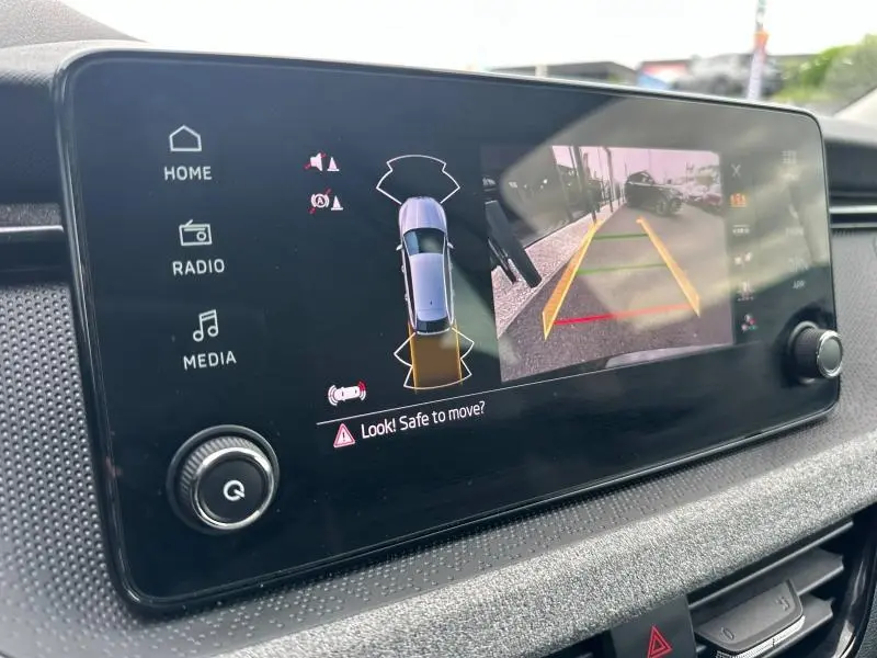 Écran tactile intérieur de la Skoda Scala noir Magic nacré montrant l’aide au stationnement avec vue caméra arrière.