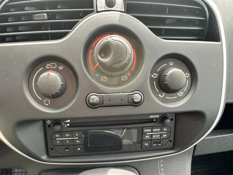 Gros plan sur la console centrale du Renault Kangoo Express blanc, montrant les commandes de climatisation et la radio intégrée.