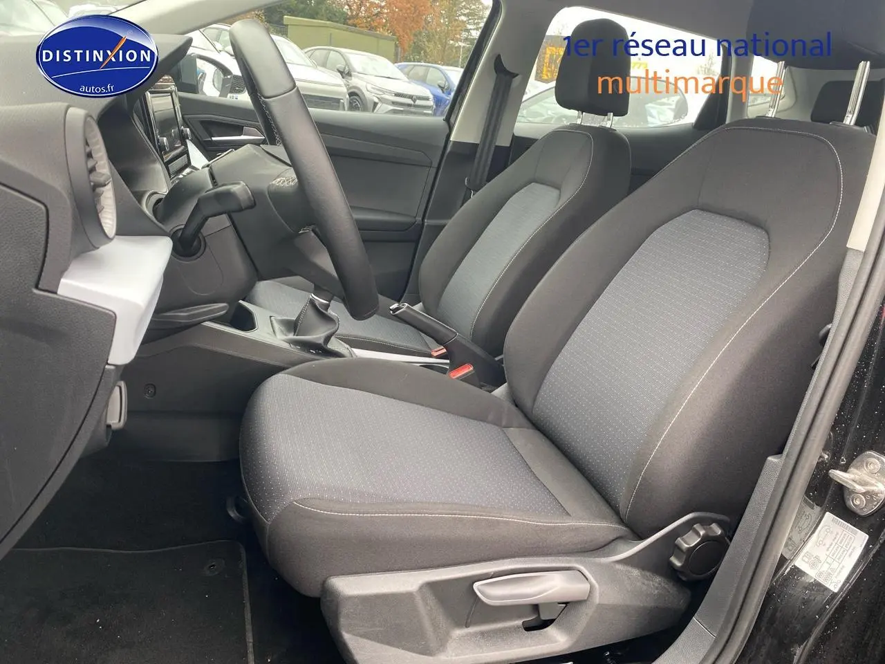 Vue intérieure côté conducteur de la SEAT Ibiza noir minuit 2025, montrant les sièges tissu gris et la boîte manuelle.