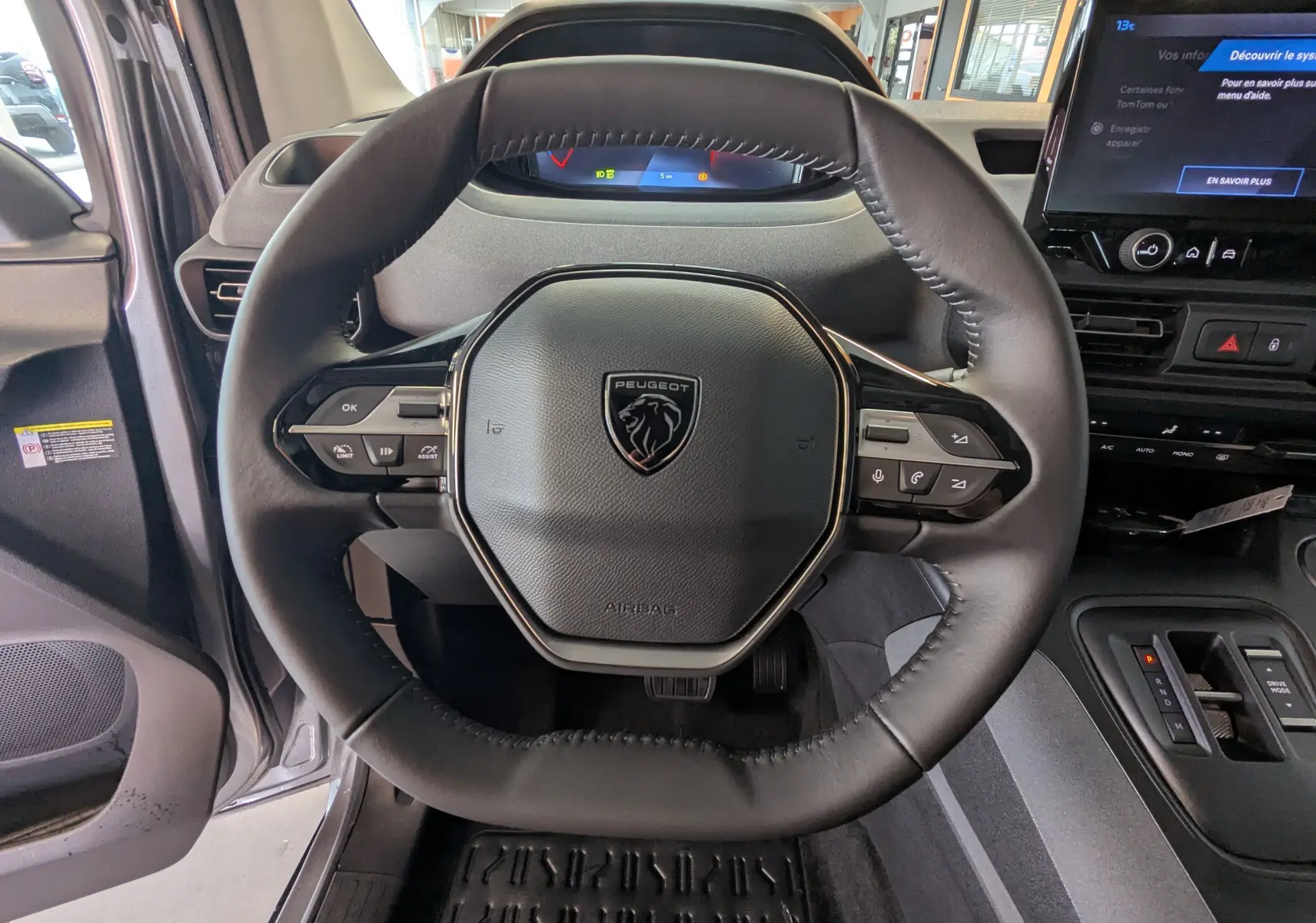 Vue rapprochée du volant cuir noir du Peugeot Rifter 2025, avec tableau de bord digital et écran tactile central.