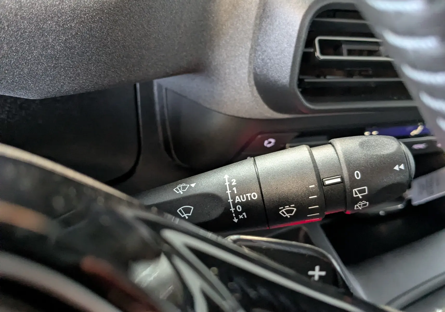 Gros plan sur la commande d’essuie-glace du Peugeot Rifter gris Artense, avec détails des réglages visibles.