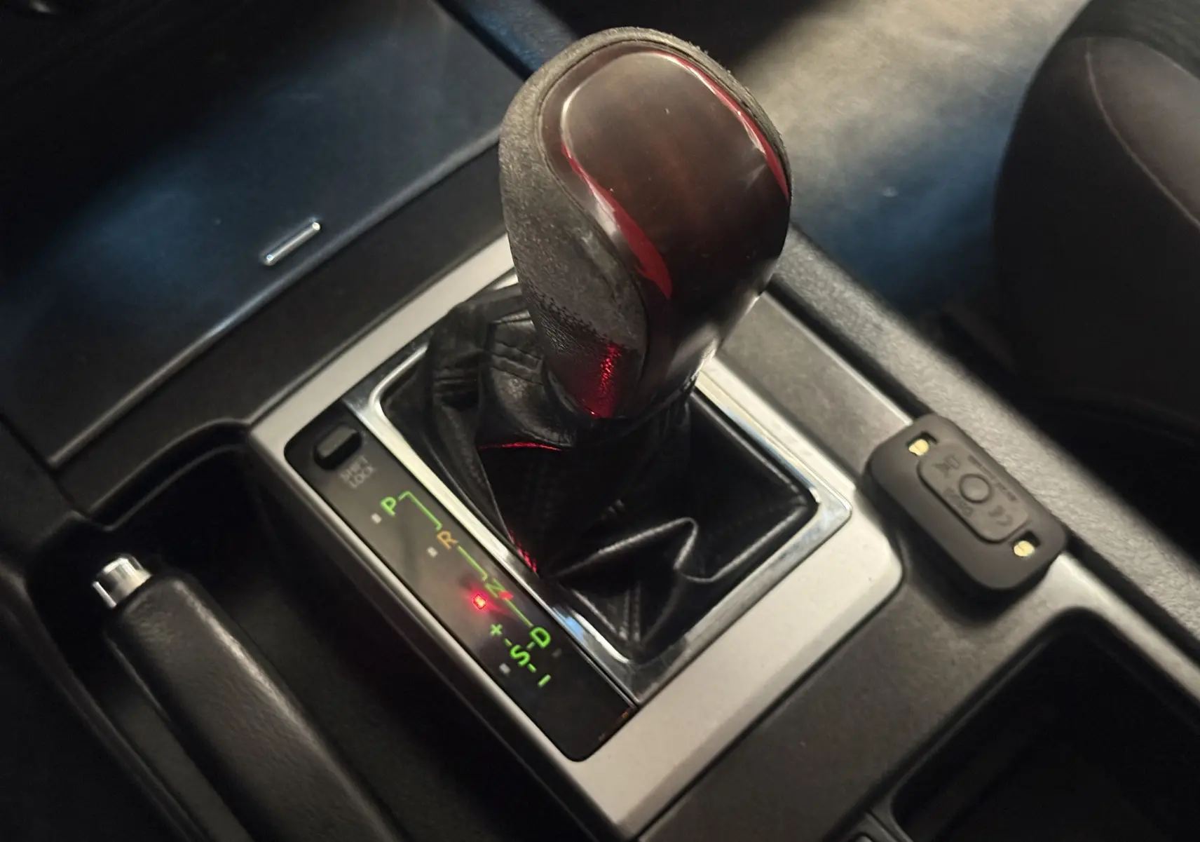 Gros plan sur le levier de vitesses automatique noir du Toyota Land Cruiser blanc, version 2.8 D-4D 2015, avec indicateurs lumineux.